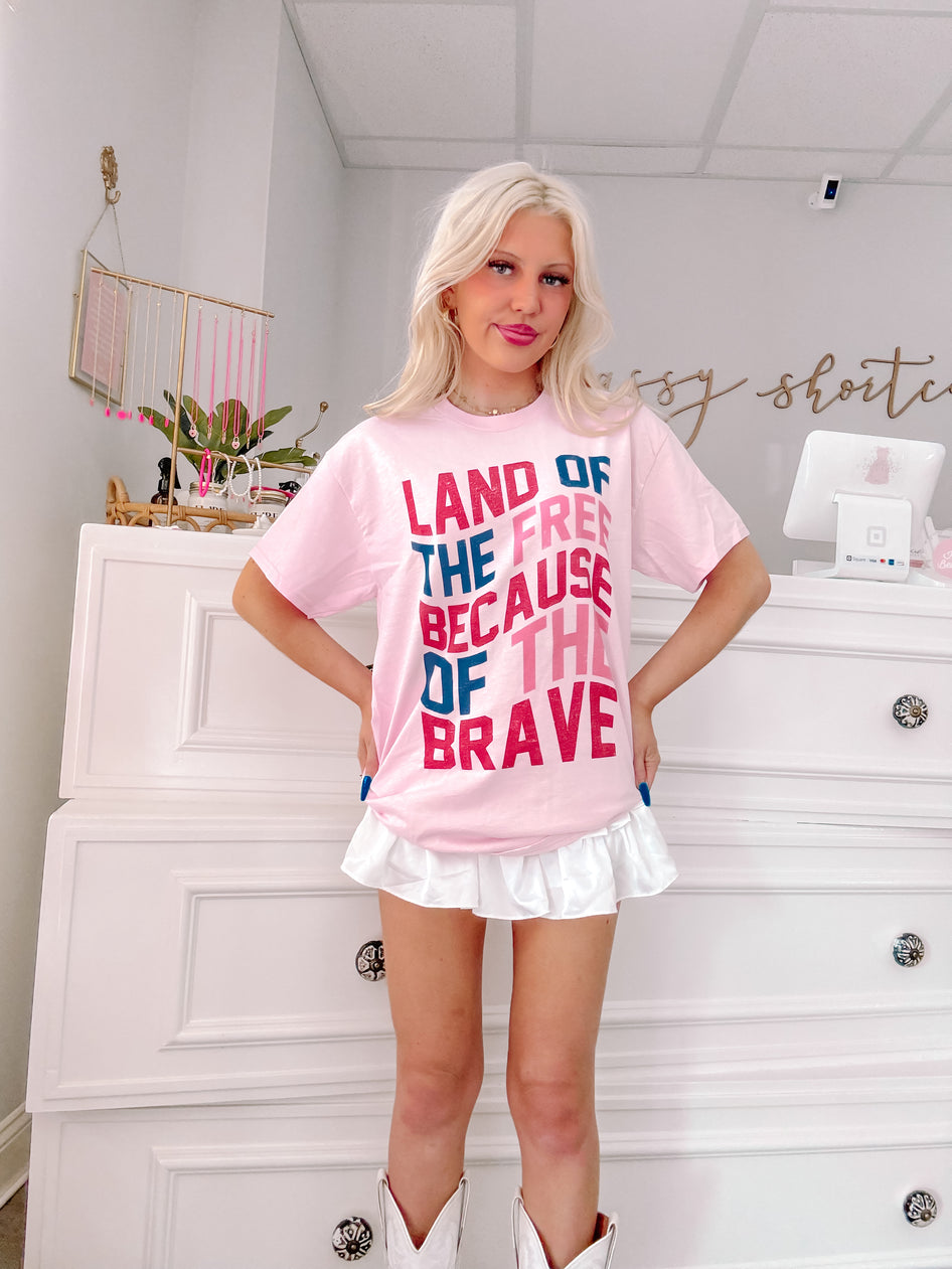 Pink patriotic tee featuring a layered typography design against a bright white background.
