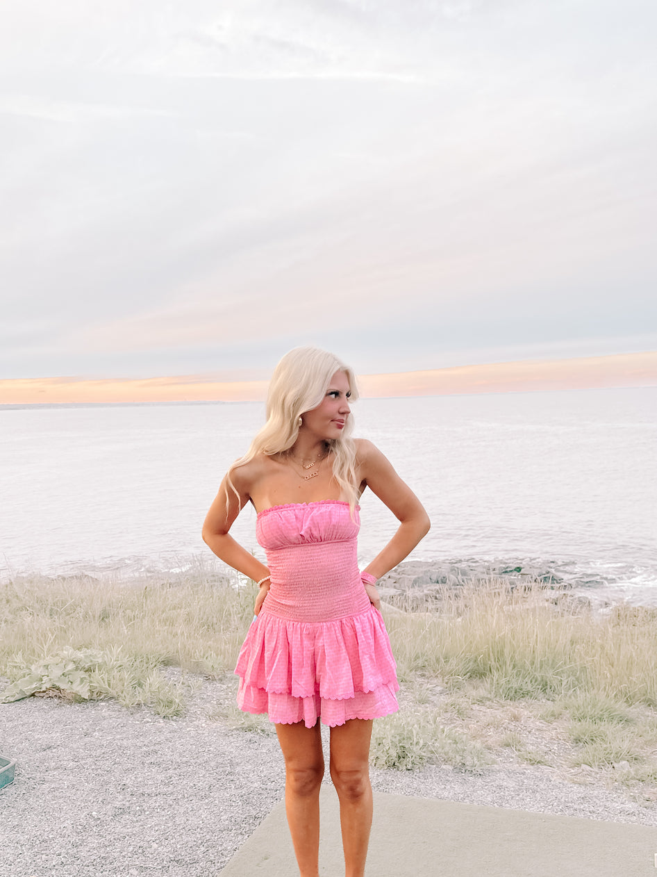 Pink tiered mini dress, worn outdoors by the ocean at sunset.
