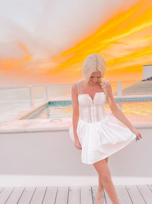 White eyelet mini dress by the pool at sunset.