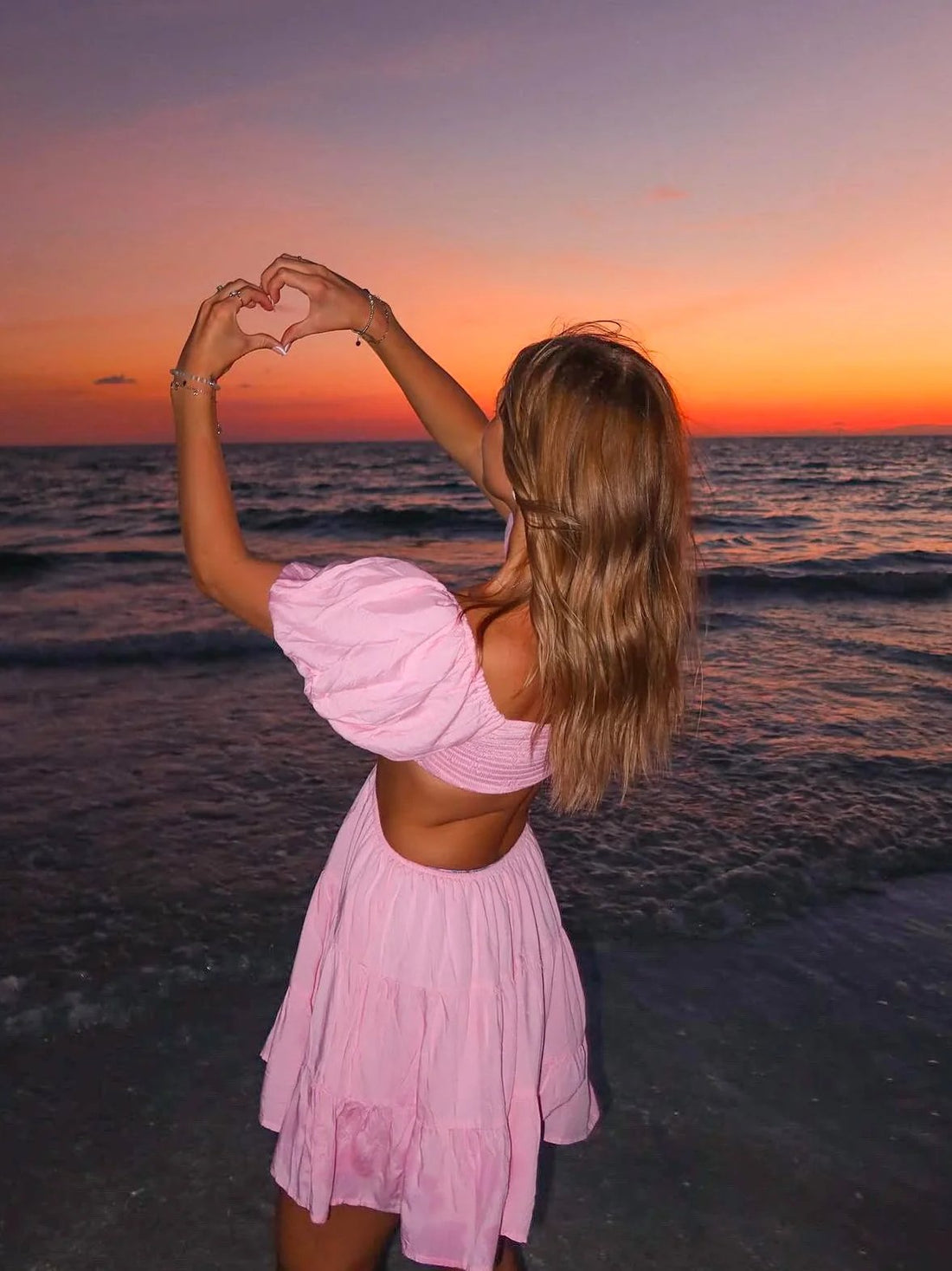 Pink tiered mini dress at sunset beach.

