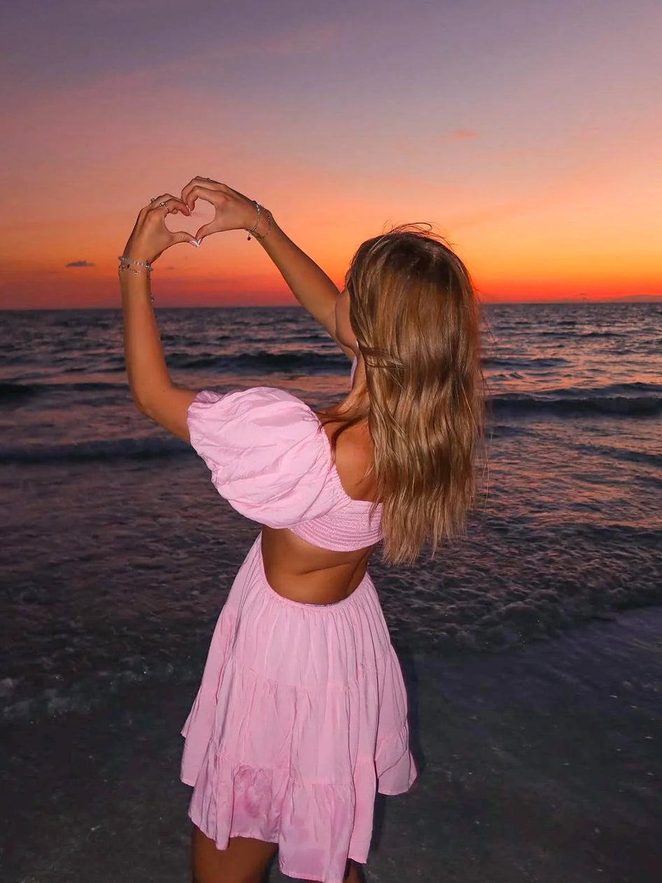 Pink tiered mini dress at sunset beach.
