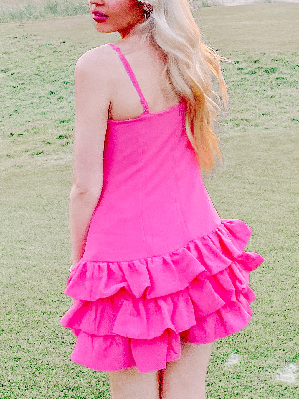 Hot pink mini dress with tiered ruffles, shown outdoors.
