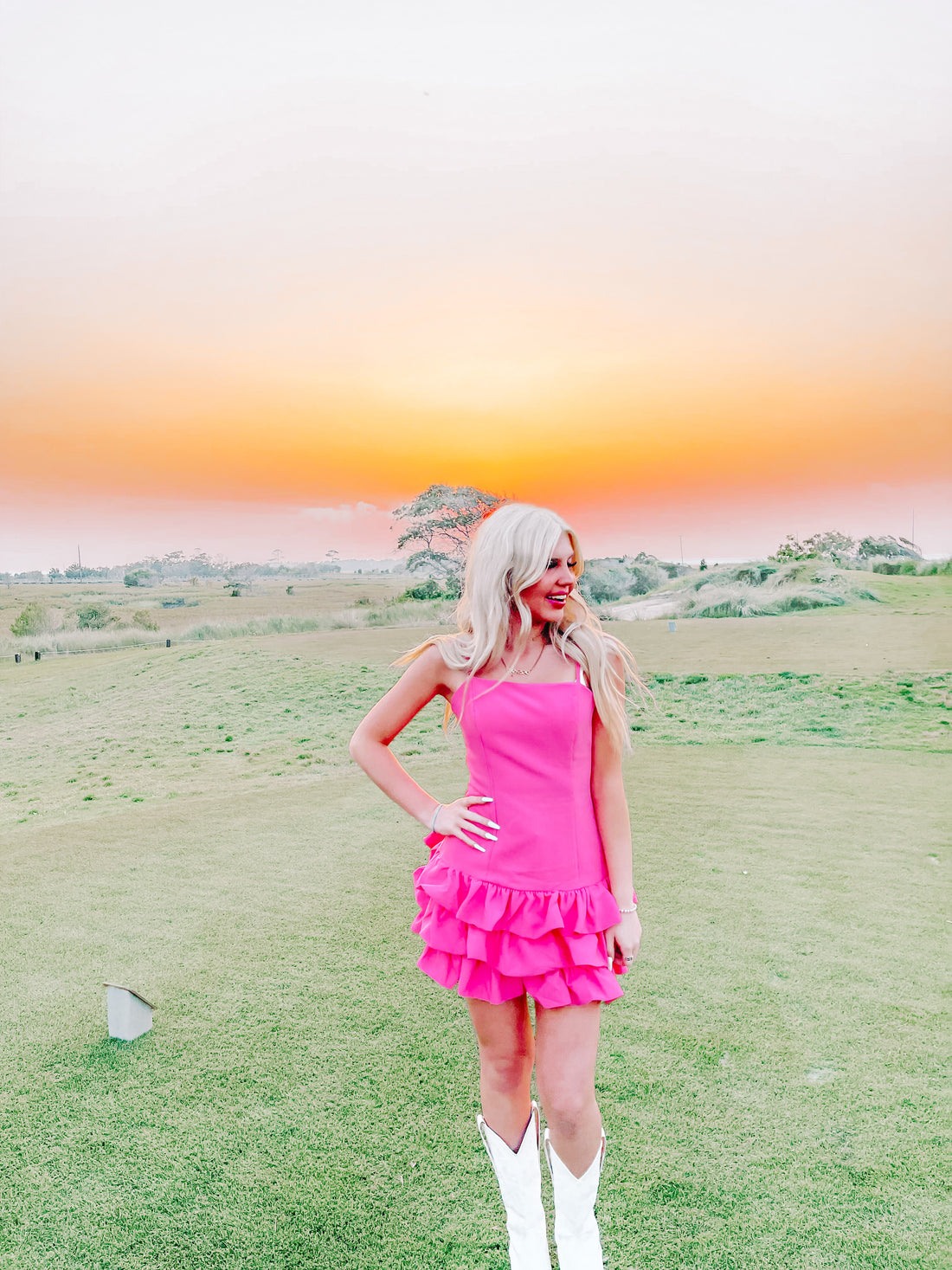 Pink dress with tiered ruffles, worn outdoors at sunset.
