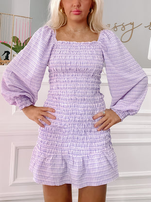 Lavender gingham smock dress with puffed sleeves and a fitted waist.
