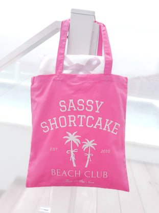 Sassy Shortcake Beach Club Tote Bag: Pink canvas tote with palm tree design, "Fun in the Sun" text.
