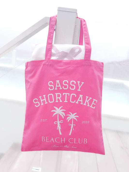 Sassy Shortcake Beach Club Tote Bag, pink canvas, white logo, palm trees, "Fun in the Sun"
