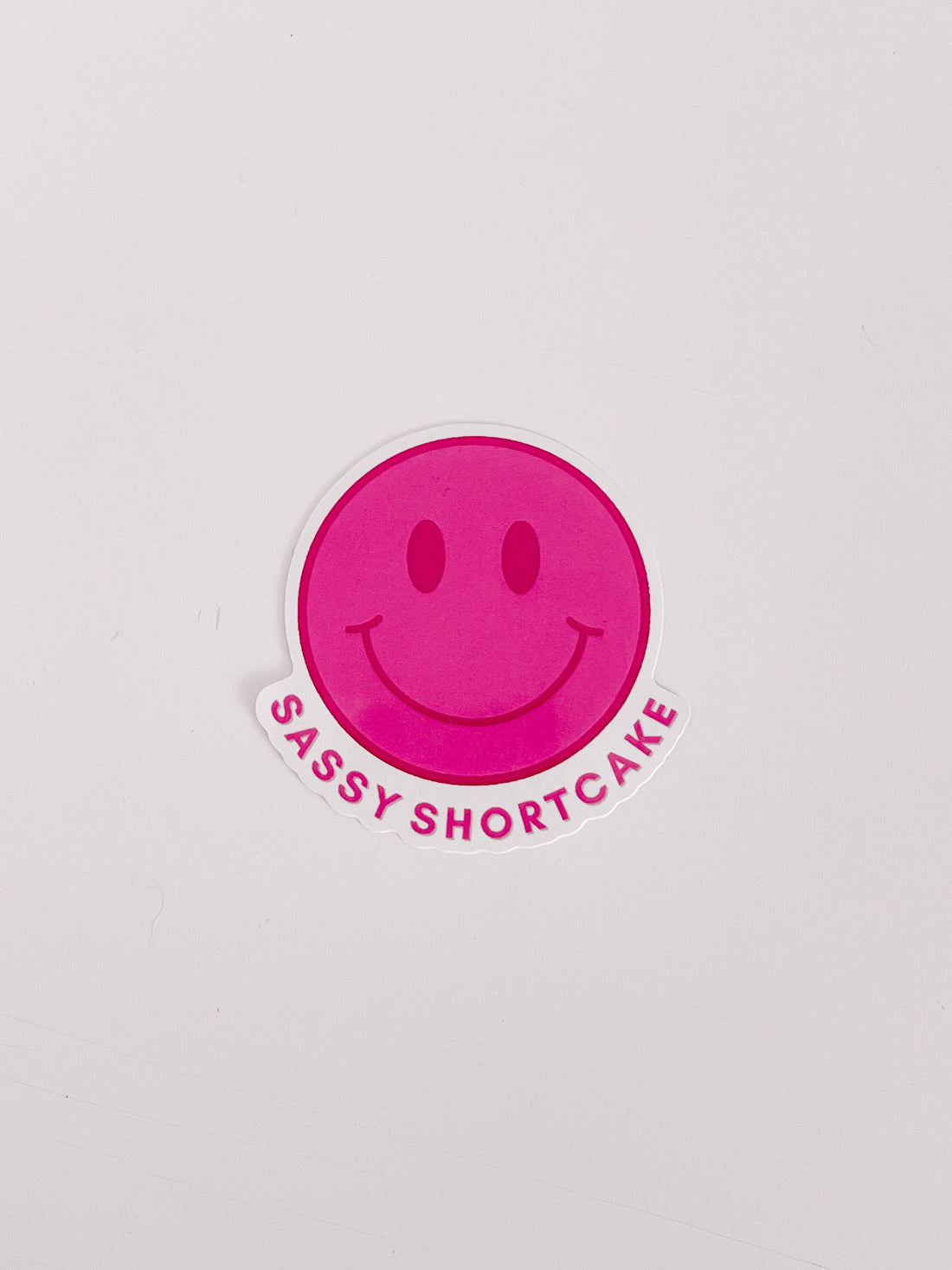 Pink smiley face sticker with "Sassy Shortcake" text on white background.

