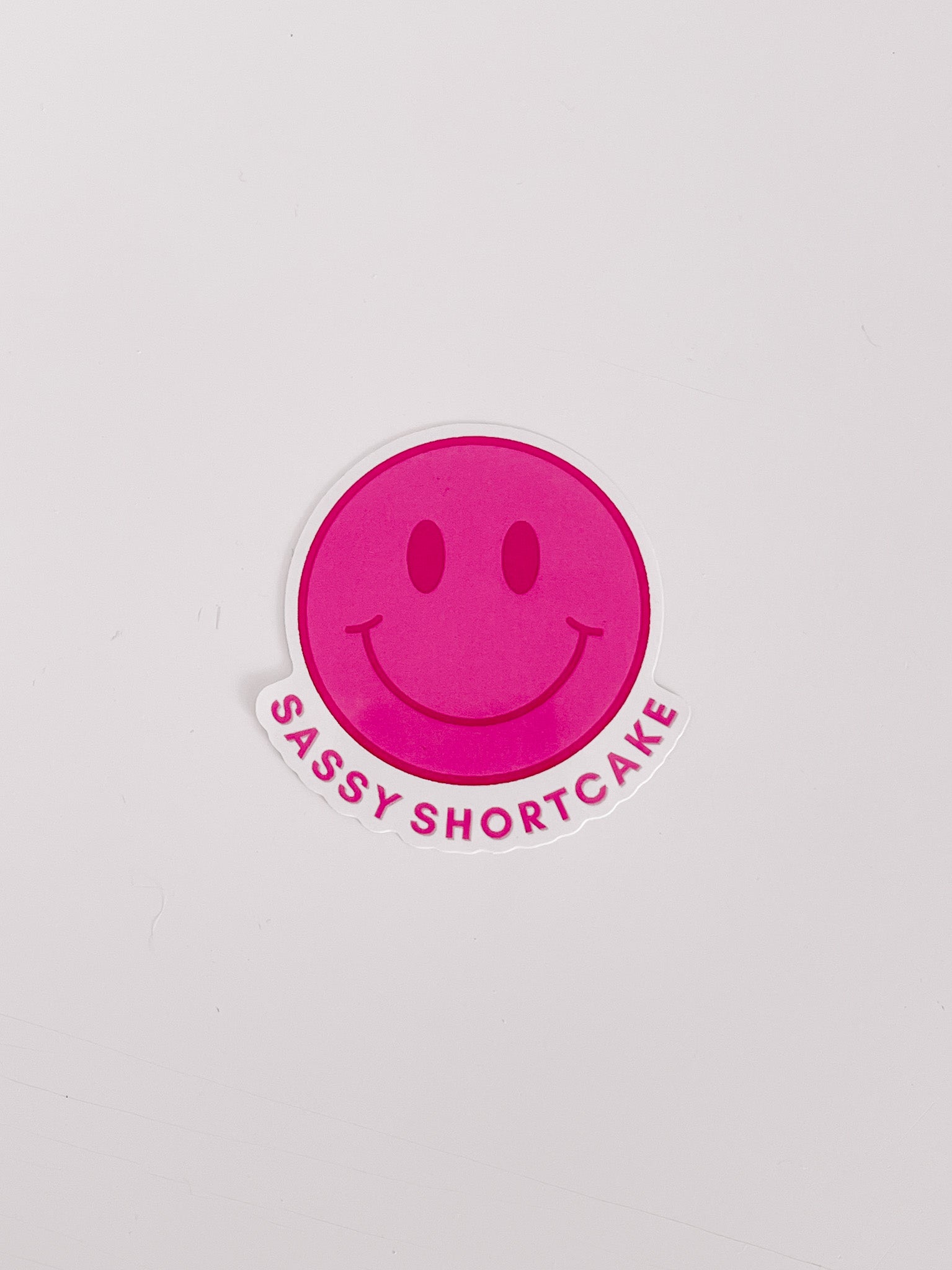 Pink smiley face sticker with "Sassy Shortcake" text on white background.
