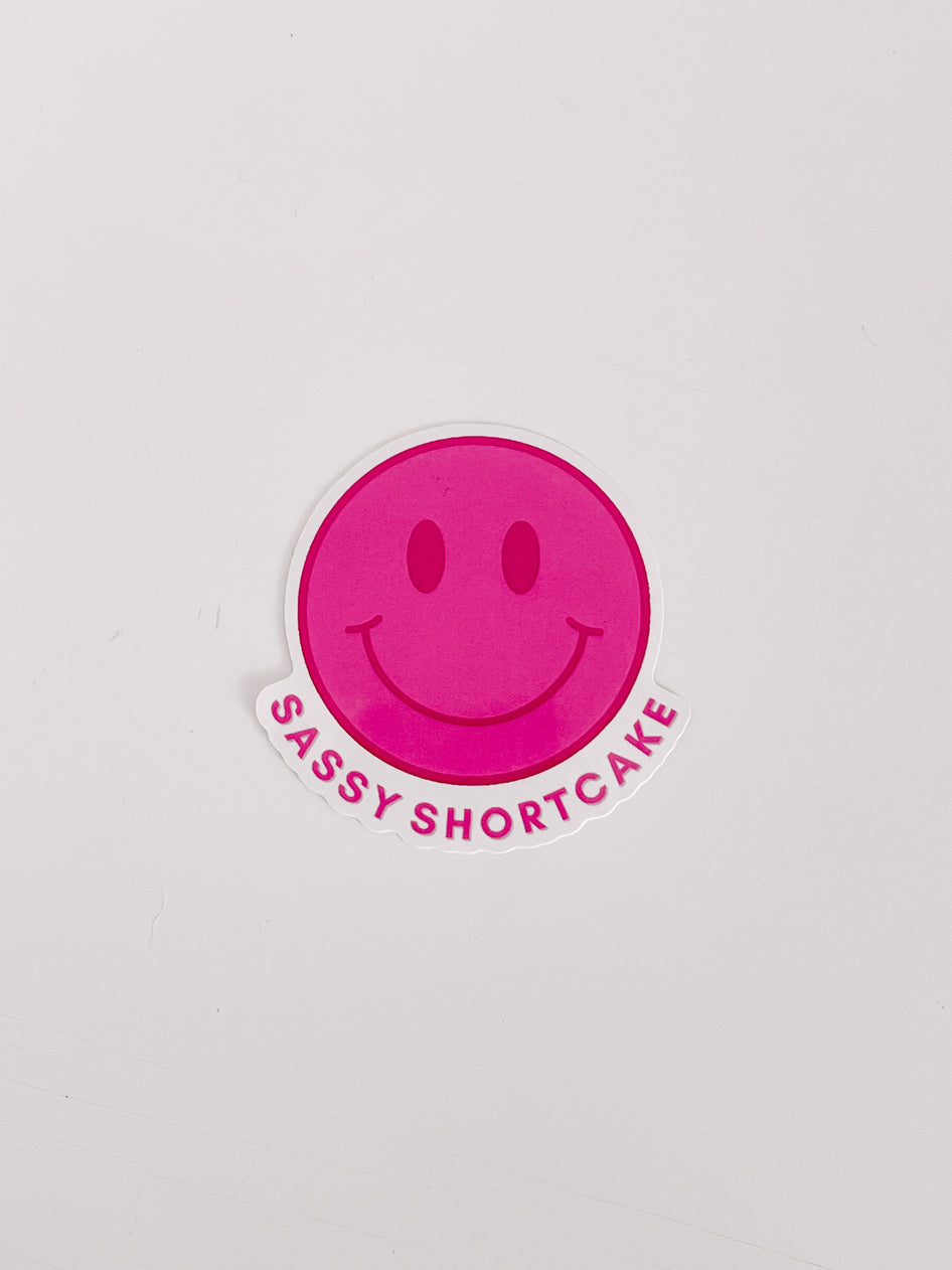 Pink smiley face sticker with "Sassy Shortcake" text on white background.

