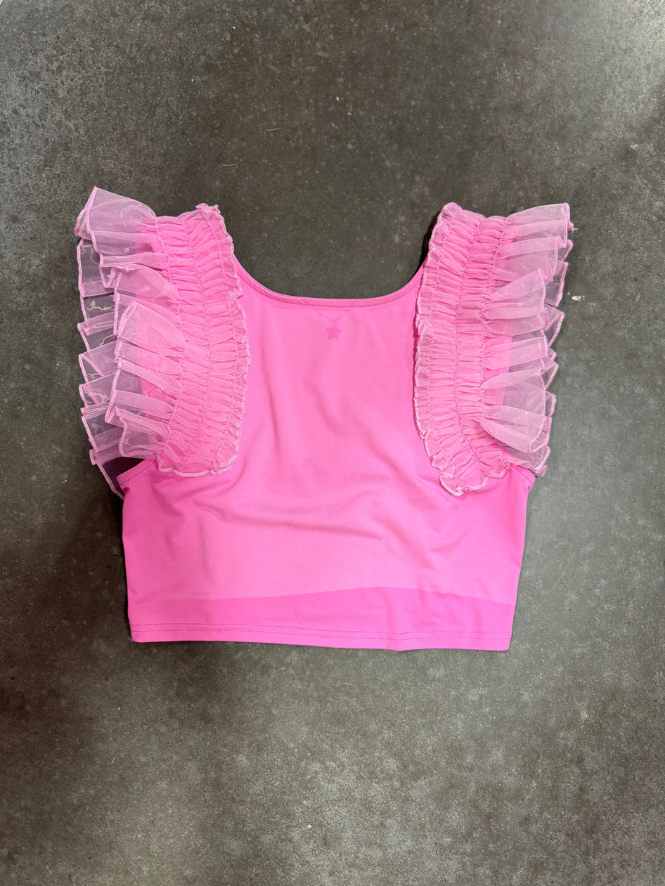 Pink crop top with sheer ruffled sleeves, shown flat lay on dark gray surface.
