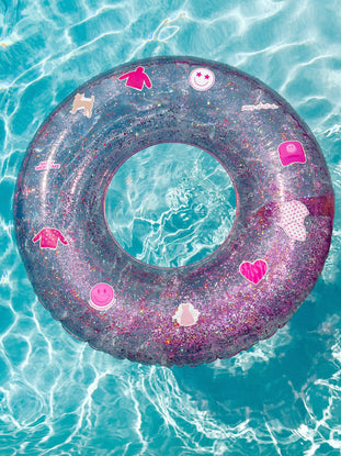 Pink glitter pool float with fun summer stickers, floating in a turquoise pool.
