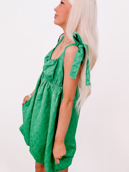 Emerald green mini dress with tie straps, shown on model against white background.
