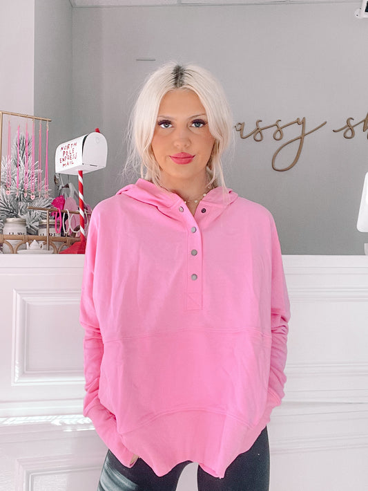 Bubblegum pink pullover hoodie with button placket, modeled against a gray wall.
