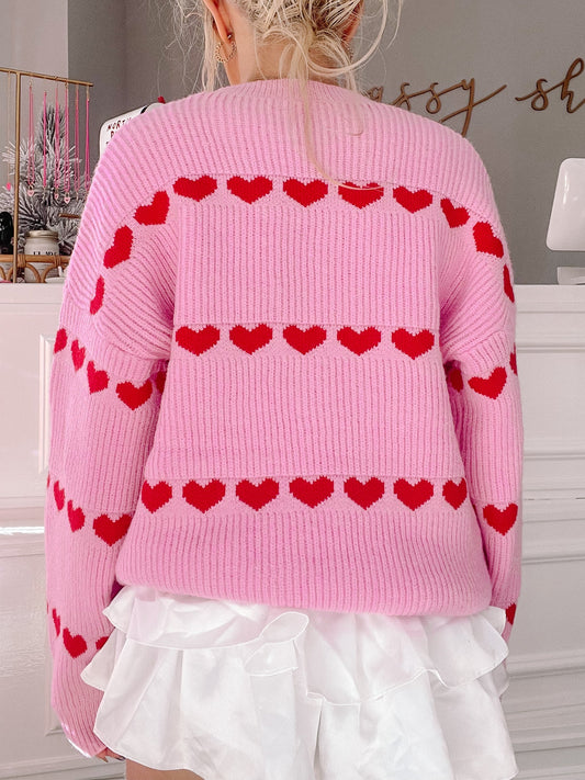 Pink knit sweater with red heart details, shown from the back.