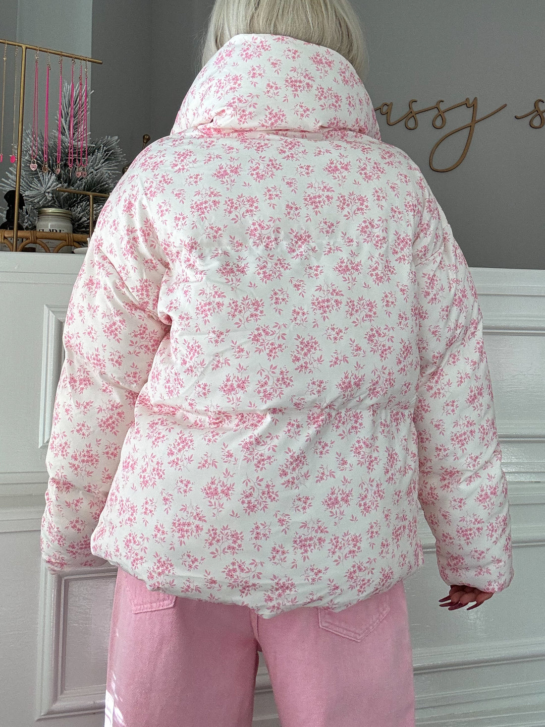 White puffer jacket with pink floral print, shown from the back.
