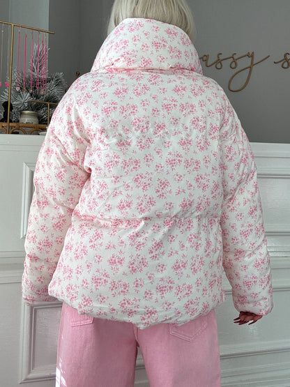 White puffer jacket with delicate pink floral print, shown from the back.
