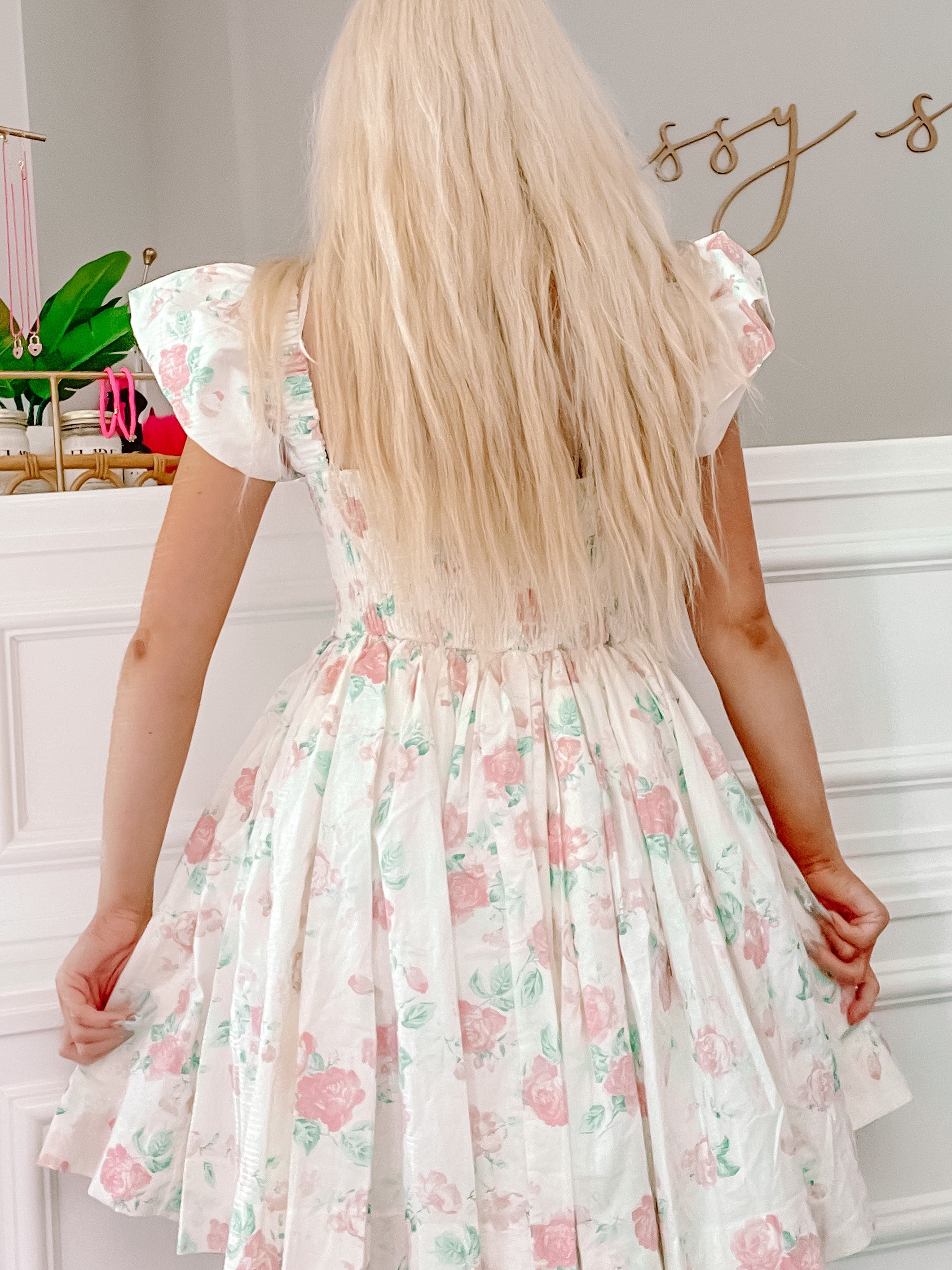 Floral mini dress, pink and green roses on a white background, viewed from the back.
