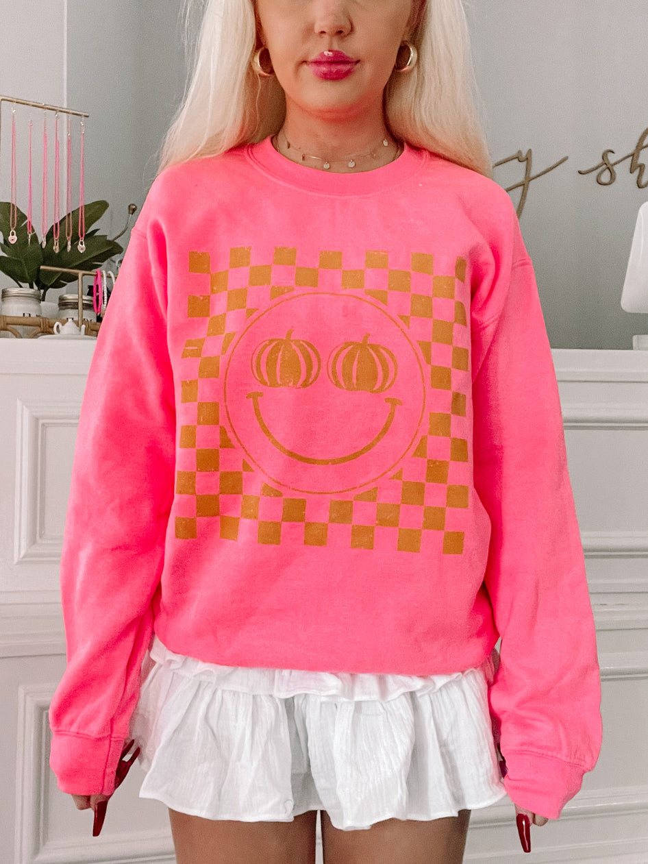 Pink Pumpkin Smiley Crewneck sweatshirt with gold checkered design
