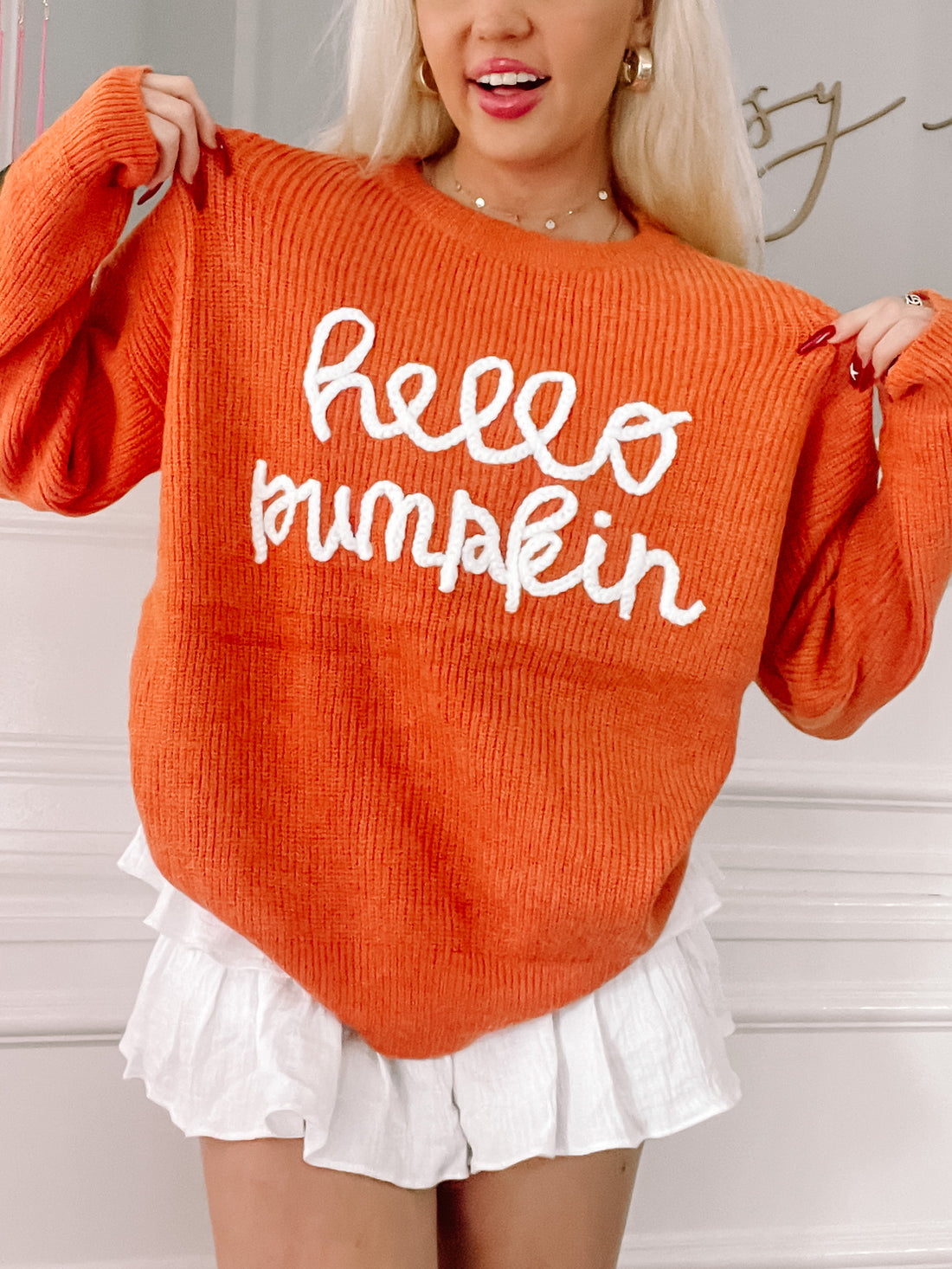 Orange knit sweater featuring a white "Hello Pumpkin" design; fall fashion.

