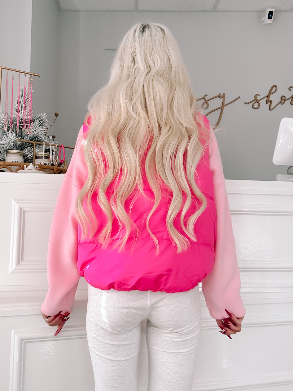 Pink puffer vest with light pink sleeves, shown from the back on a model.
