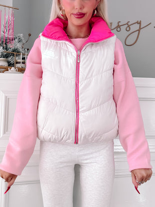 White and pink puffer vest with zipper closure, modeled over a pink sweater.
