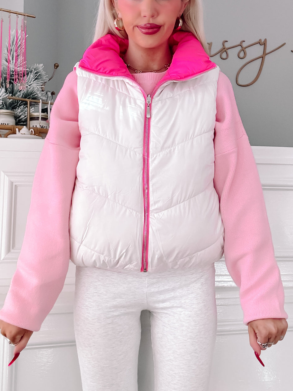 White and pink puffer vest with zipper closure, modeled over a pink sweater.
