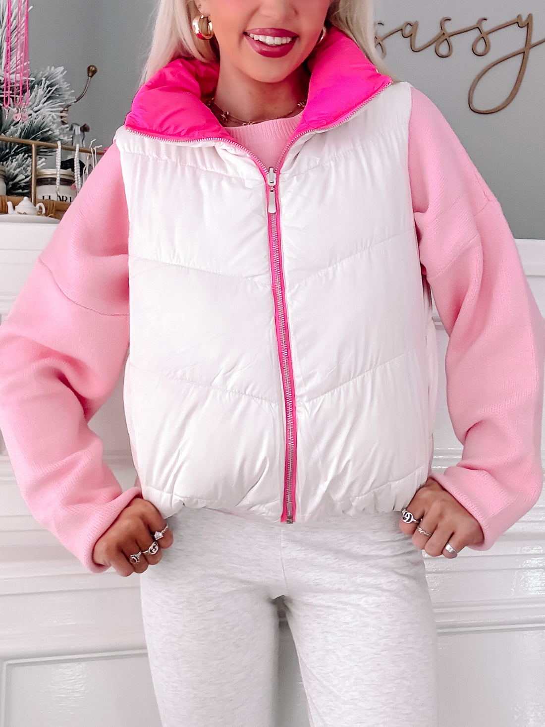 White and pink puffer vest with a zipper, styled with a pink sweater.
