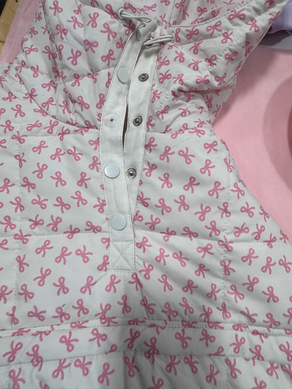 White quilted jacket featuring a pink bow pattern, shown buttoned.
