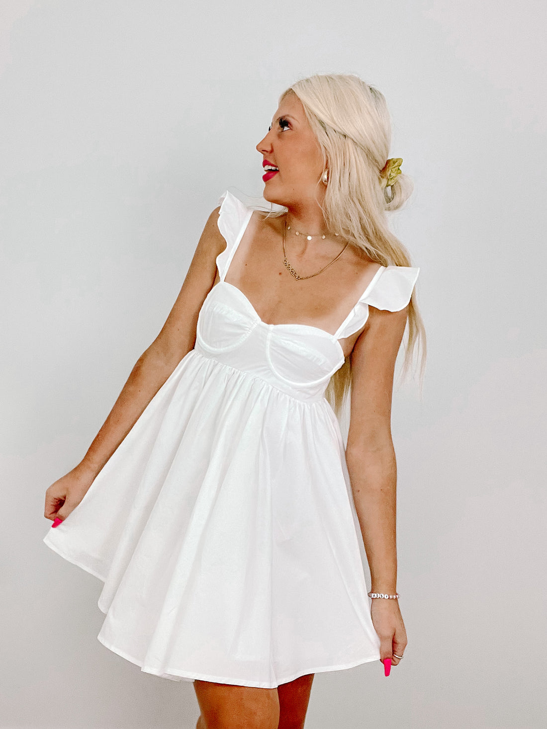 White eyelet sundress with ruffled straps, styled against a neutral backdrop.
