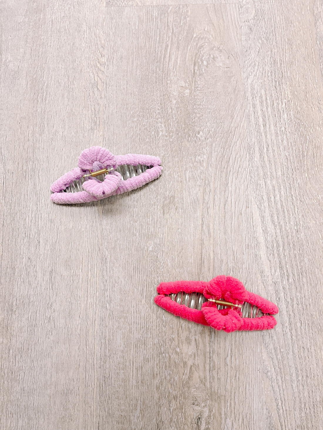 Pink and red fuzzy claw clips on wood background
