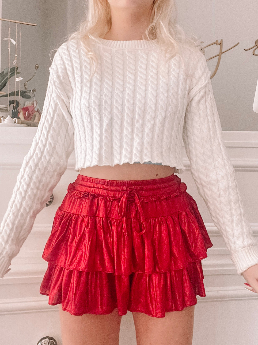 Red tiered ruffle mini skirt paired with a cream cable knit sweater.
