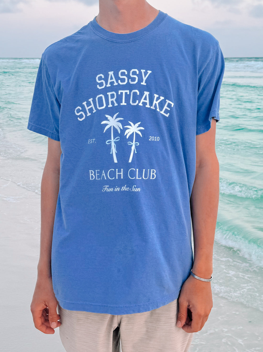 Blue Sassy Shortcake Beach Club tee with palm tree graphic, "Fun in the Sun" text.
