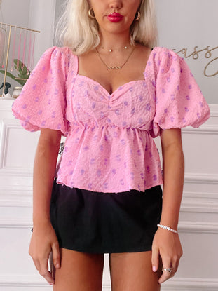 Pink puff-sleeve top with purple floral print; square neck, fitted waist.
