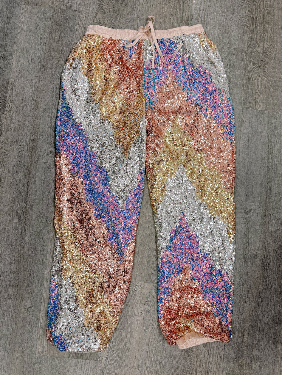 Multicolor sequin pants with a drawstring waist, shown flat lay on a wood background.
