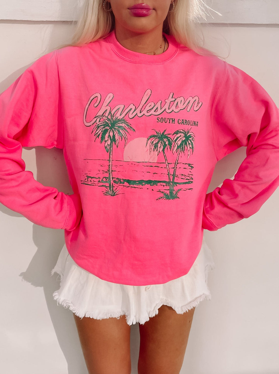 Pink Charleston crewneck sweatshirt featuring a palm tree graphic and "Charleston, South Carolina" text.
