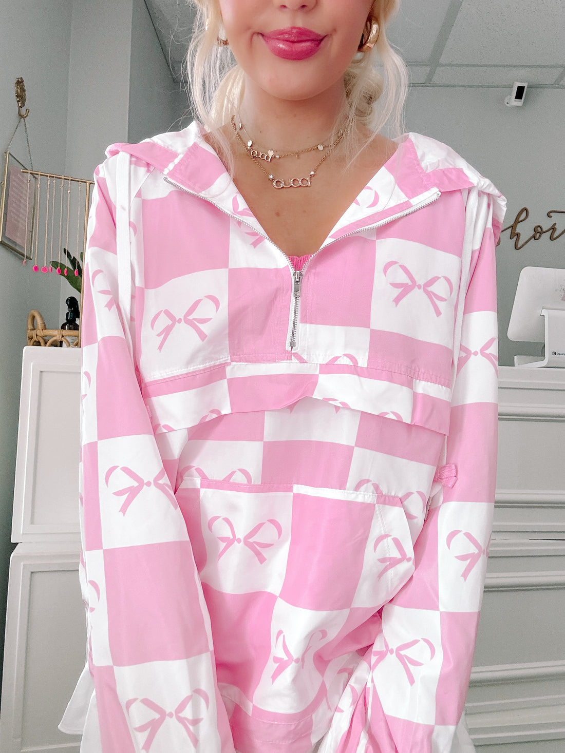 Pink and white checkered windbreaker with bow print, zipper closure.
