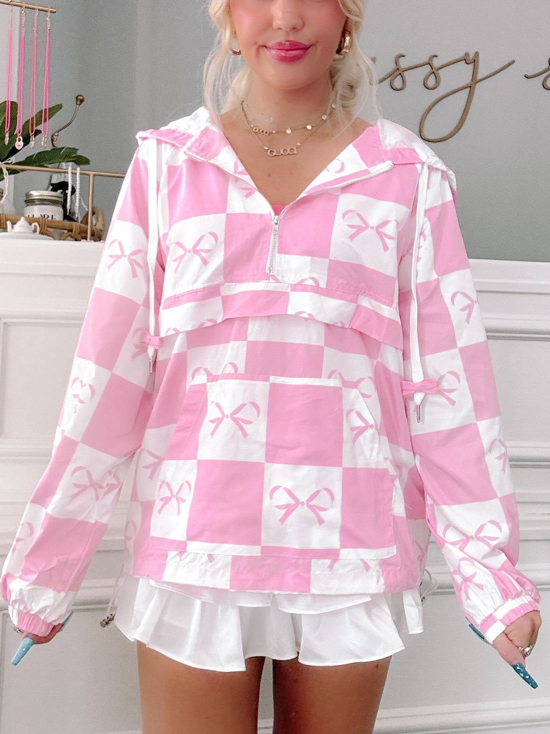 Pink bow windbreaker with checkered pattern, zip-up front and pockets.
