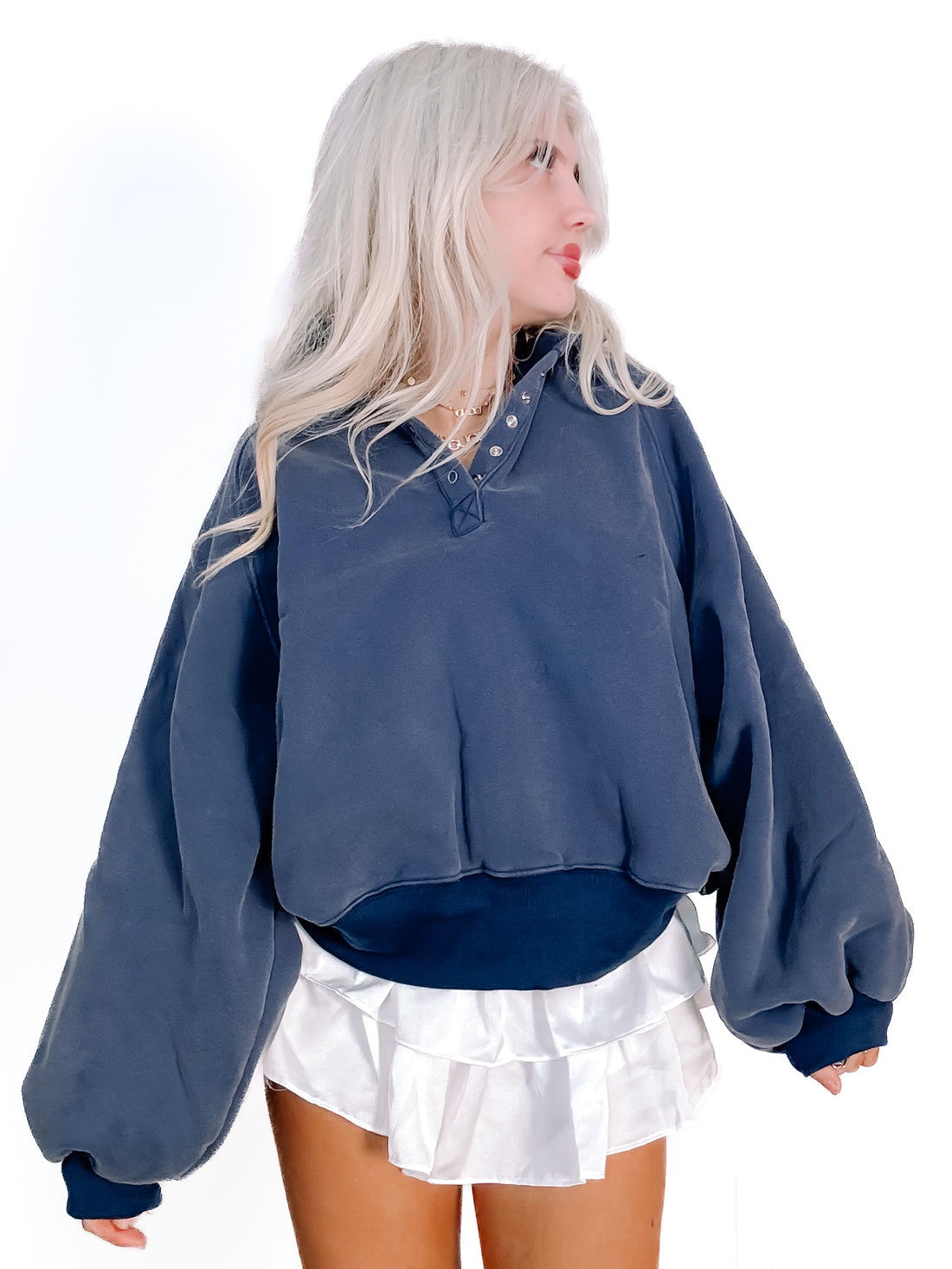 Navy blue pullover sweatshirt with balloon sleeves, styled with a white ruffled mini skirt.
