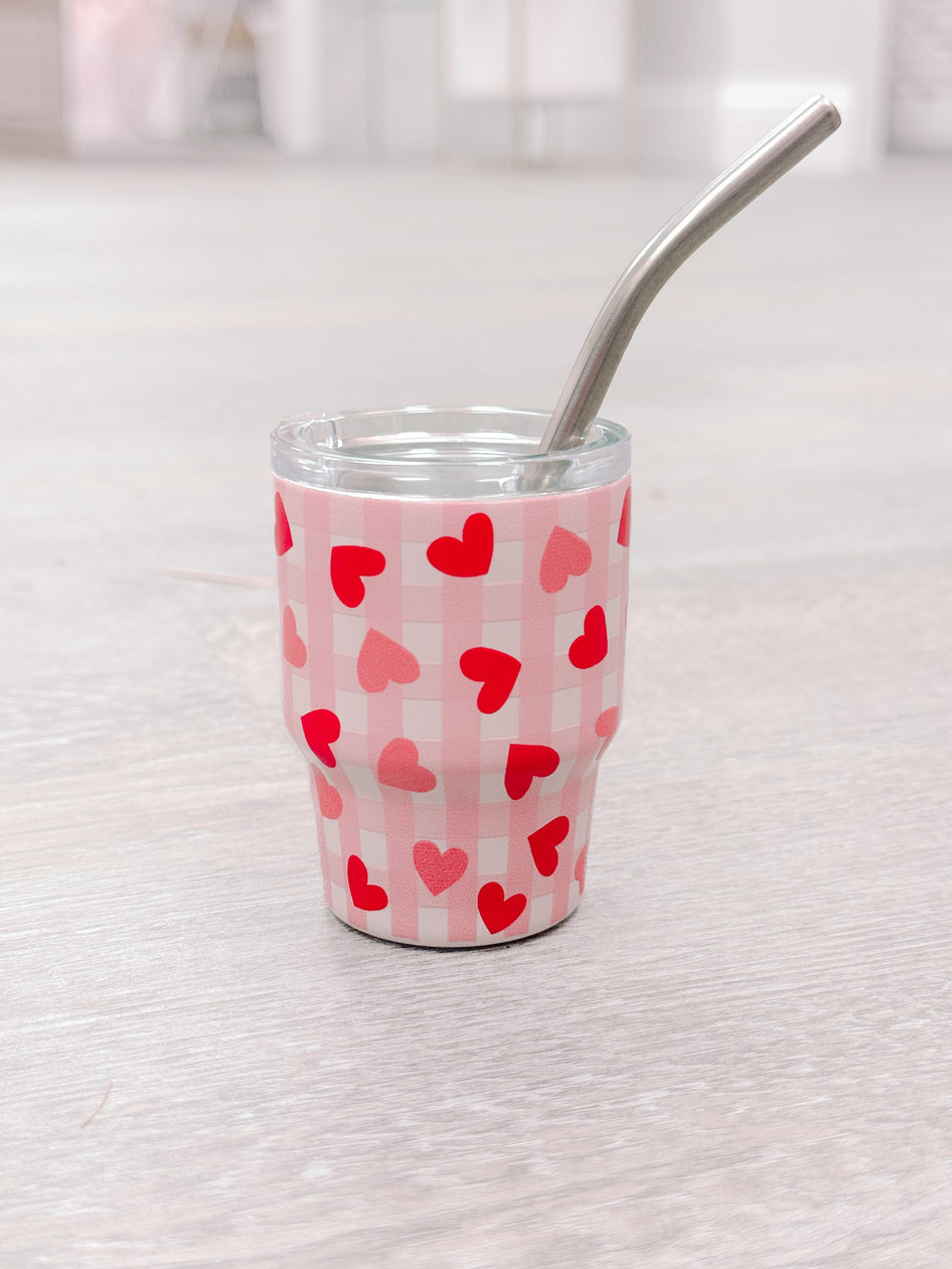 Pink tumbler with red hearts and gingham design, stainless steel straw.
