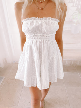 White eyelet Coconut Bliss mini dress with ruffled neckline and cinched waist.
