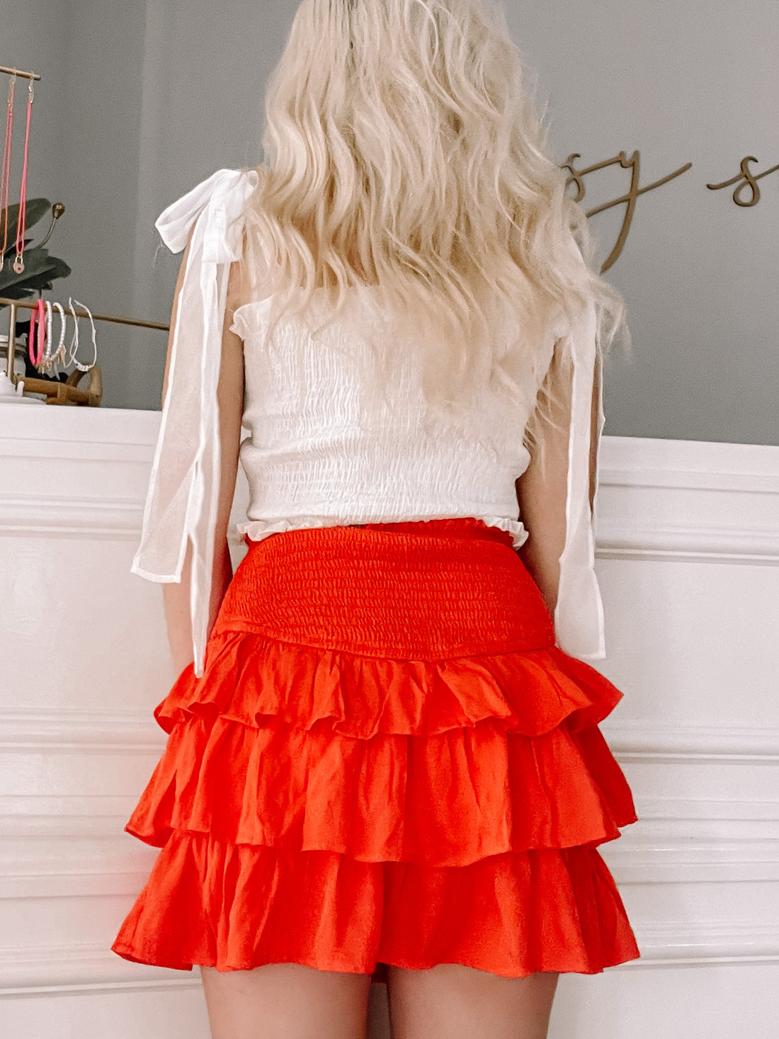 Tiered orange mini skirt with ruffle detailing, shown from the back.

