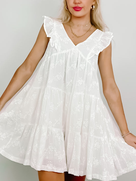 White eyelet mini dress with tiered ruffle details and sleeveless V-neck.