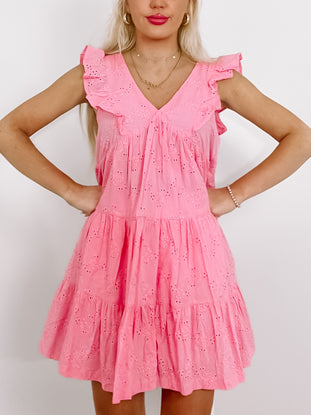 Pink eyelet mini dress with tiered ruffle details and V-neck.
