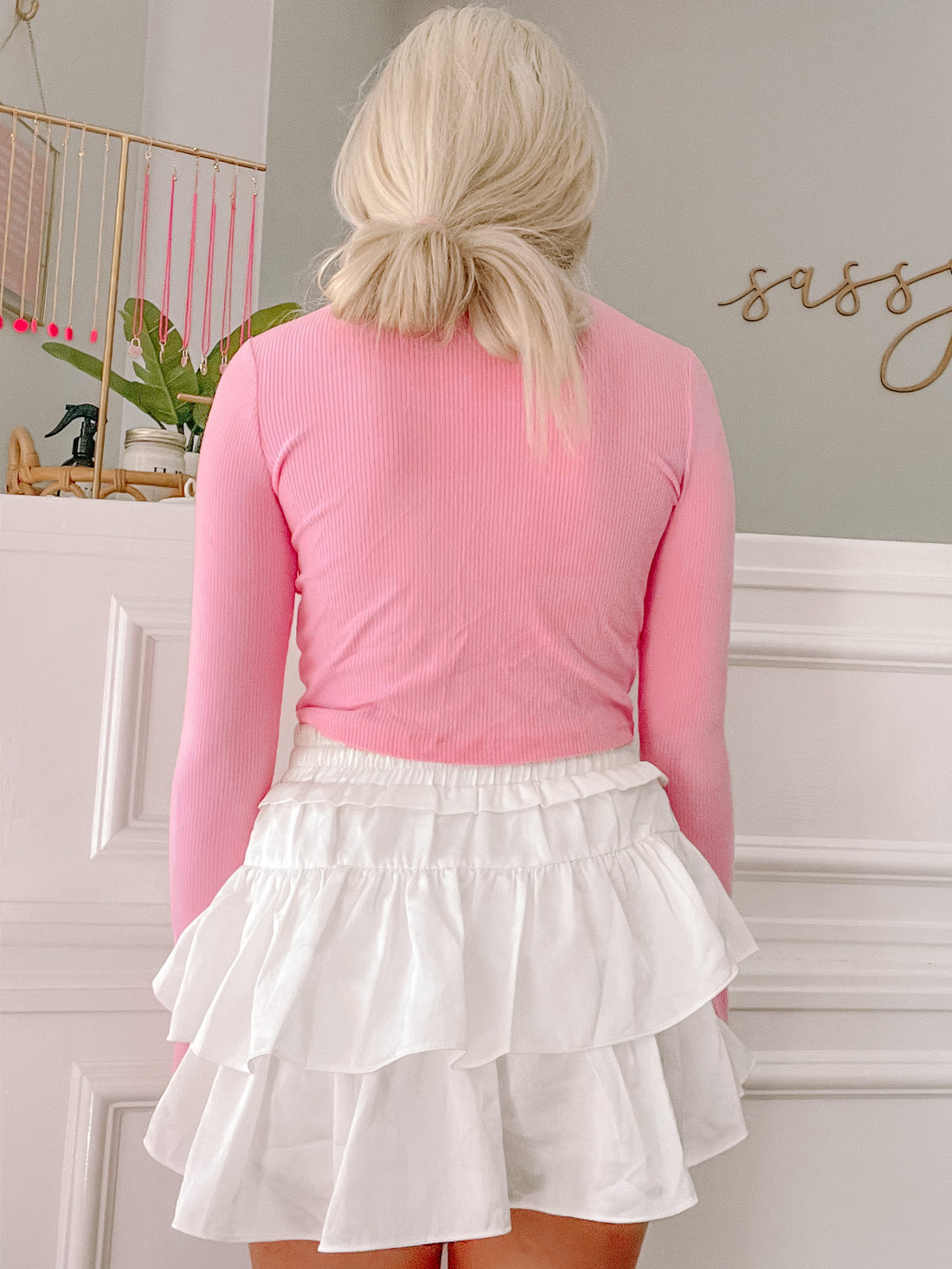 Pink ribbed long-sleeve top paired with a white ruffled mini skirt.

