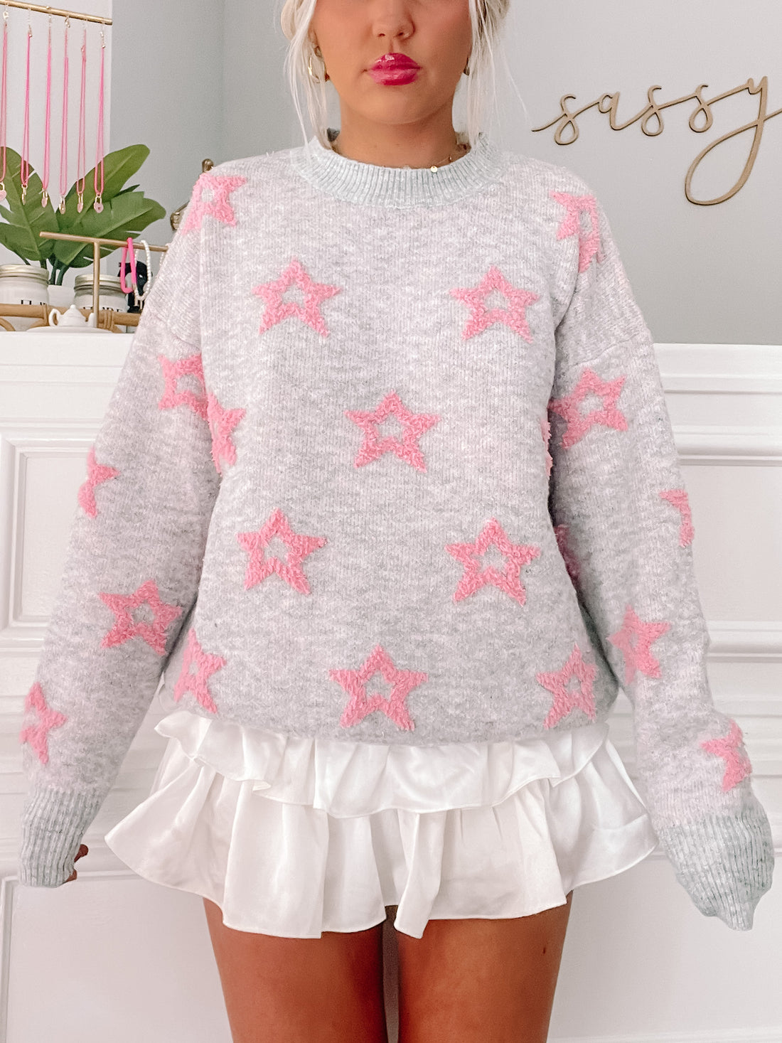 Cozy gray sweater adorned with pink star details, shown on a model.
