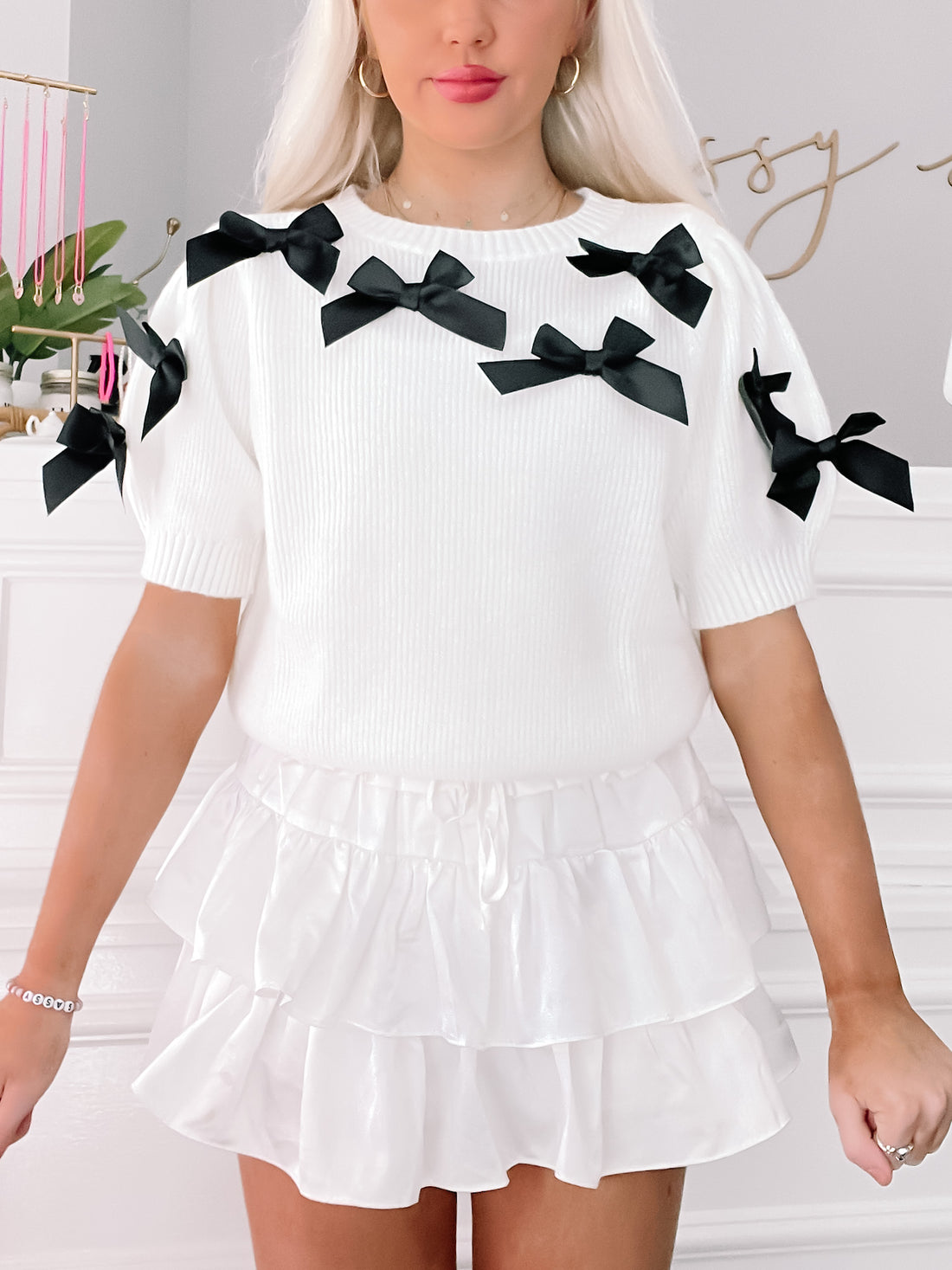 White ribbed knit sweater with black bows, short sleeves; "Put a Bow On It" sweater.
