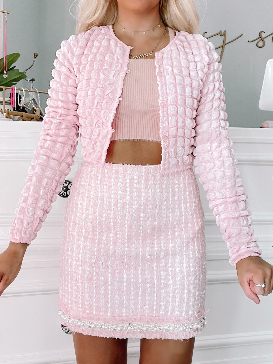 Pink textured cardigan and skirt set; the cardigan has a puffed sleeve detail.
