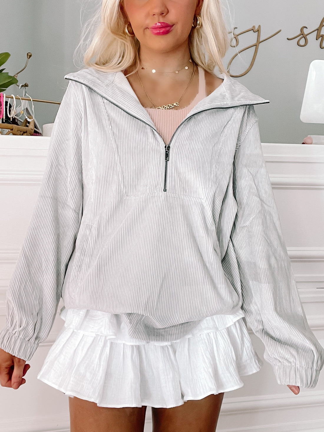 Grey corduroy zip-up jacket styled with a white ruffle skirt.
