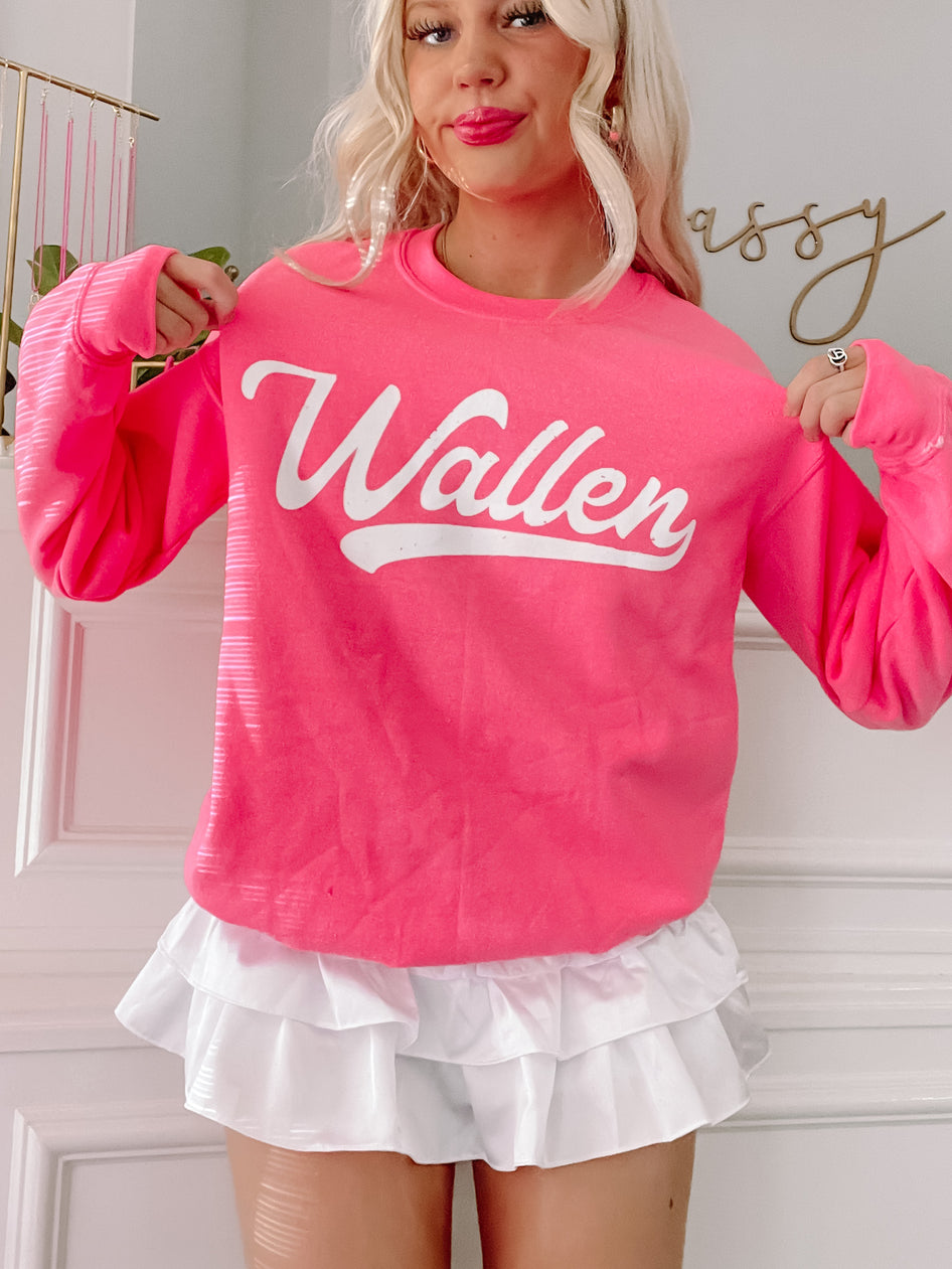 Hot pink crewneck sweatshirt with white lettering; styled with a white ruffled skirt.
