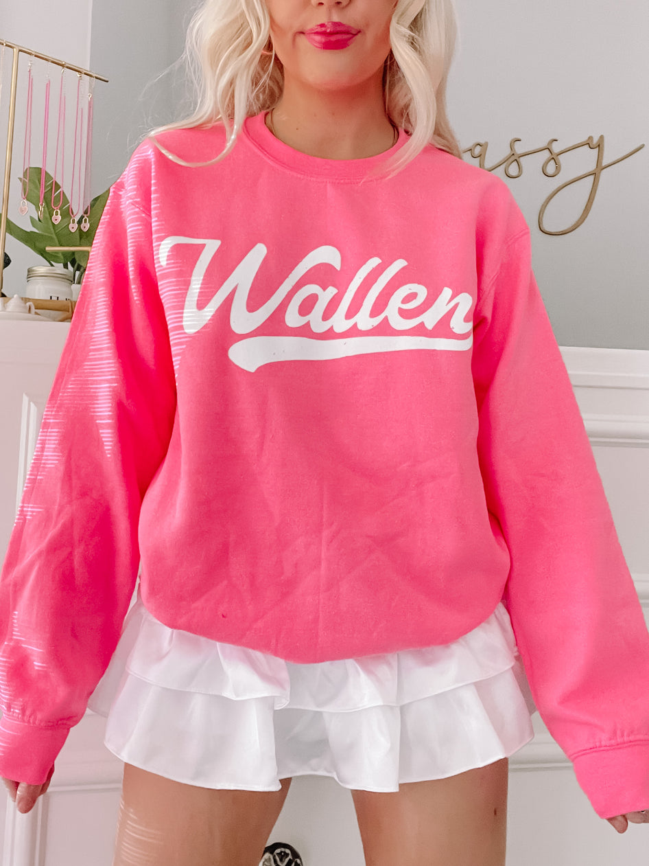 Bright pink crewneck sweatshirt with white lettering, modeled with a white ruffled skirt.
